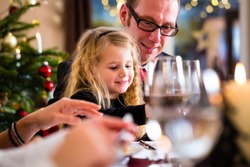 parents and children toasting with wine and water at Christmas eve dinner 