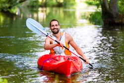 man driving with kayak on forest river
