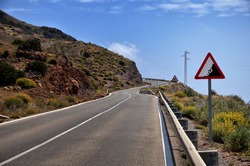 Warning sign in a red triangle on a mountain road