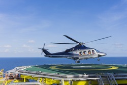 Aviation transportation. View of commercial helicopter depart after taking offshoreworkers on oil and gas platform with background of South China sea.