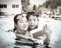 teenager siblings brother and sister make selfie in the swimming pool with special waterproof camera close up photo