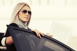 Fashion business woman with financial papers by her car 
