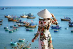Vietnamese lady with Ao Dai Vietnam traditional dress and conical hat wait at the harbor, Fishing Harbour Mui Ne Vietnam