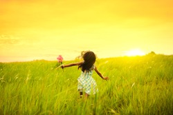 Little girl running on meadow with sunset