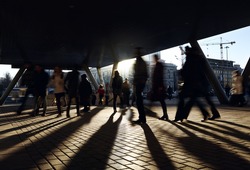 People walking near the metro station. City background with backlight sun.