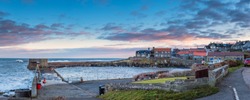Craster Harbour and Village Panorama, which is a small fishing village on the Northumberland coast, with a small harbour and views to the ruins of Dunstanburgh Castle