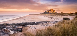 Golden Bamburgh Castle Panorama / Bamburgh Castle on the Northumberland coastline, bathed in late afternoon golden sunlight