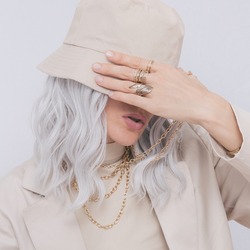 Urban street style Blonde. Details of everyday look. Casual beige outfit and accessories. Bucket hat and rings. Trendy Minimalist fashion
