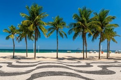 Copacabana beach with palms and mosaic of sidewalk in Rio de Janeiro, Brazil. Copacabana beach is the most famous beach in Rio de Janeiro. Sunny cityscape of Rio de Janeiro