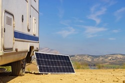 Portable solar photovoltaic panel, charging battery at camper car rv. Camping on nature, van life.