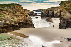 People walking on Cathedrals Beach at low tide, Playa las Catedrales in Ribadeo, province of Lugo, Galicia. Cantabric coast in northern Spain. Tourist place.