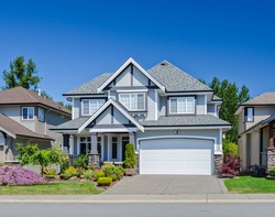 Big custom made luxury house with nicely trimmed and landscaped front yard and driveway to garage in the suburb of Vancouver, Canada.