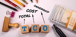 TCO Total Cost of Ownership. Office objects and money on a white background.