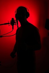 Voiceover artist actor recording voice overs in professional audio studio with large diaphragm cardioid microphone.