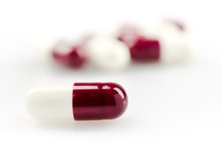 Medical theme. Dark red capsules on a white surface. Closeup