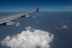 Viewed from airplane windows with a wing, blue sky and white cloud