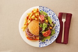 Low fat healthy salad against unhealthy greasy burger