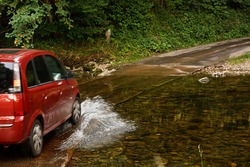 Family Car fording a river at ford an old fashioned way of crossing water without building a bridge