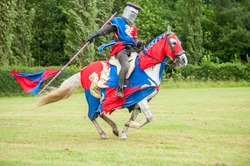 Medieval knight costume on a horse and man with flag 
