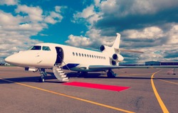 White reactive private jet, the front landing gear and a ladder on blue sky and clouds