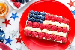 American flag sandwich with fresh fruit like raspberries, banana and blueberries on rye bread with patriotic decoration for Independence Day celebration