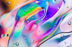 Closeup of oil drops motion on water surface.  Colorful abstract macro background of oil drops on water surface with air bubbles inside
