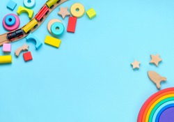 Wooden toys rainbow, train and blocks on blue background with blank space for text. Top view, flat lay.