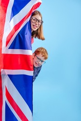 Schoolchildren wearing eye glasses standing near Great Britain Union Jack flag on blue background with blank space for text