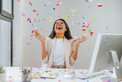 Young business woman having fun time catching confetti