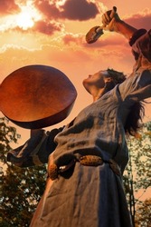 Shaman woman performs a ritual with a tambourine at sunset in the forest. Shamanic ritual. Ethnic traditions