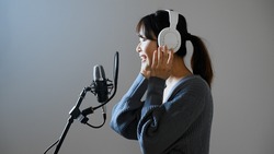 A young woman recording a song.	