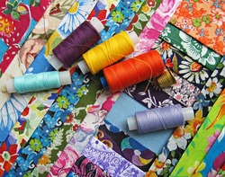 Assorted fabrics. Patchwork fabric. Patchwork sewing. Threads, thimbles and patchwork fabrics.