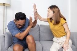 Asian Wife Hit Her Cheating Husband on Couch at Home  for  a Couple Fighting and Domestic Violence Concept