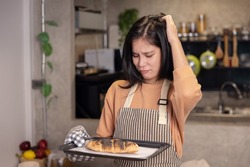 Upset Asian Woman Look at the Her Overcooked Burnt Bread from the Oven