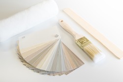 Renovation or home improvement items including a siding color sampler, paint brush, roller sleeve and stir stick on white