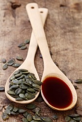Pumpkin seed oil and seeds in wooden spoons