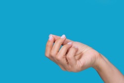 Closeup view stock color photography of one beautiful manicured female hand isolated on bright blue background. Woman making gesture as if holding something invisible or virtual object with fingers