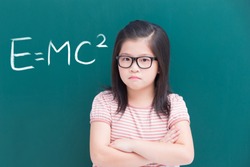 cute girl look you and feel upset with e=mc2 on green chalkboard