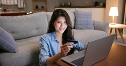 asian woman shopping on the internet and pay bill by credit card with laptop at home