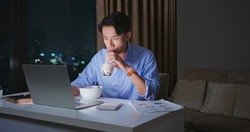 asian young businessman is eating instant noodles and drinking tapioca ball tea while he overtime working at home