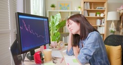 asian woman has stock market or cryptocurrency investment from home by computer and she is depressed about her failure