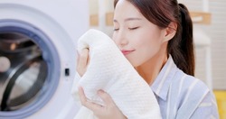 Asian housewife smell clean blanket happily at home