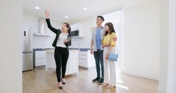 asian young couple with real estate agent visiting house for sale or rent - realtor introduces building at kitchen