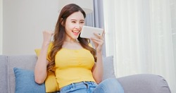 asian woman earns cryptocurrency from gami-fi or NFT mobile game at home