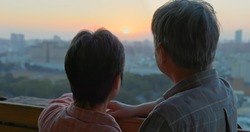 back view of senior asian couple looking outside from home