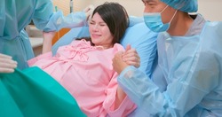 asian pregnant woman in delivery room is preparing to give birth and husband is comforting her in hospital