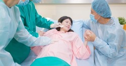asian pregnant woman in delivery room is preparing to give birth and husband is comforting her in hospital