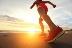 Woman Runner feet running on the beach at sunrise closeup on shoe. woman fitness sunrise jog workout wellness concept. asian