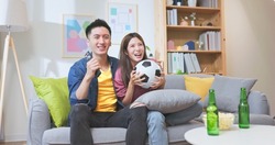 asian couple watching soccer game together with joy and excitement the man is holing a remote control 