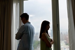 silhoutte of asian couple has a serious argue in front of the window at home - they turn around face another side against each other